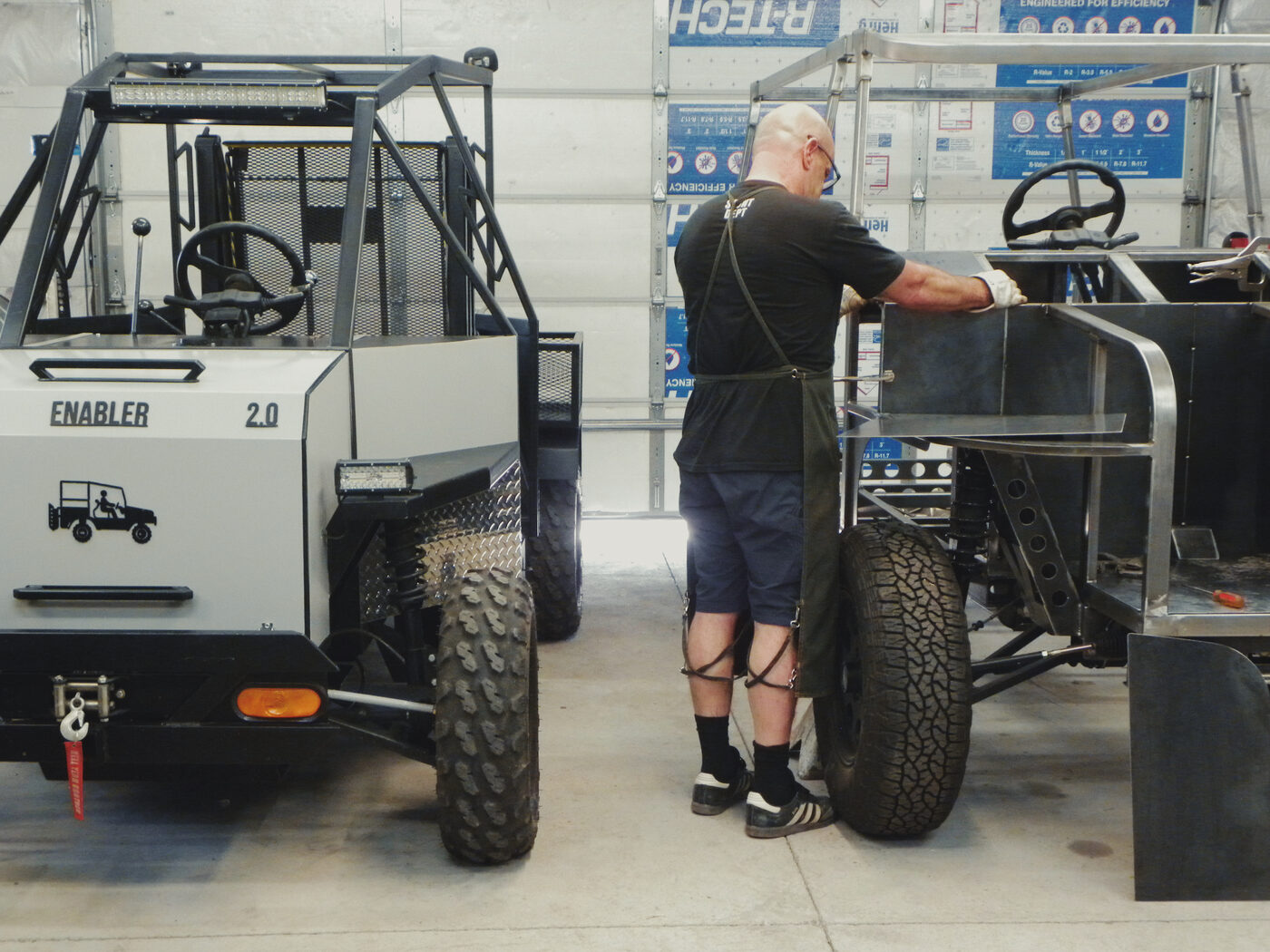 The finished Enabler 2.0 parked beside an unfinished Enabler 2.1 chassis in the shop, front view