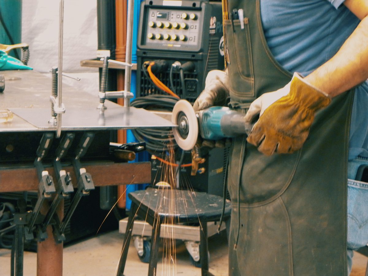 Cutting steel plate with an angle grinder, sparks streaming from the cut