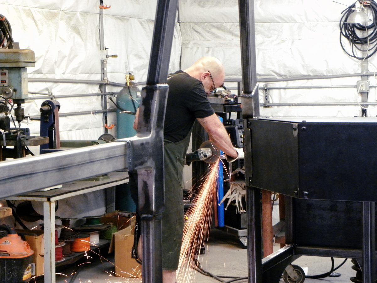 Fabricator grinding a weld on the vehicle frame in the Albuquerque shop