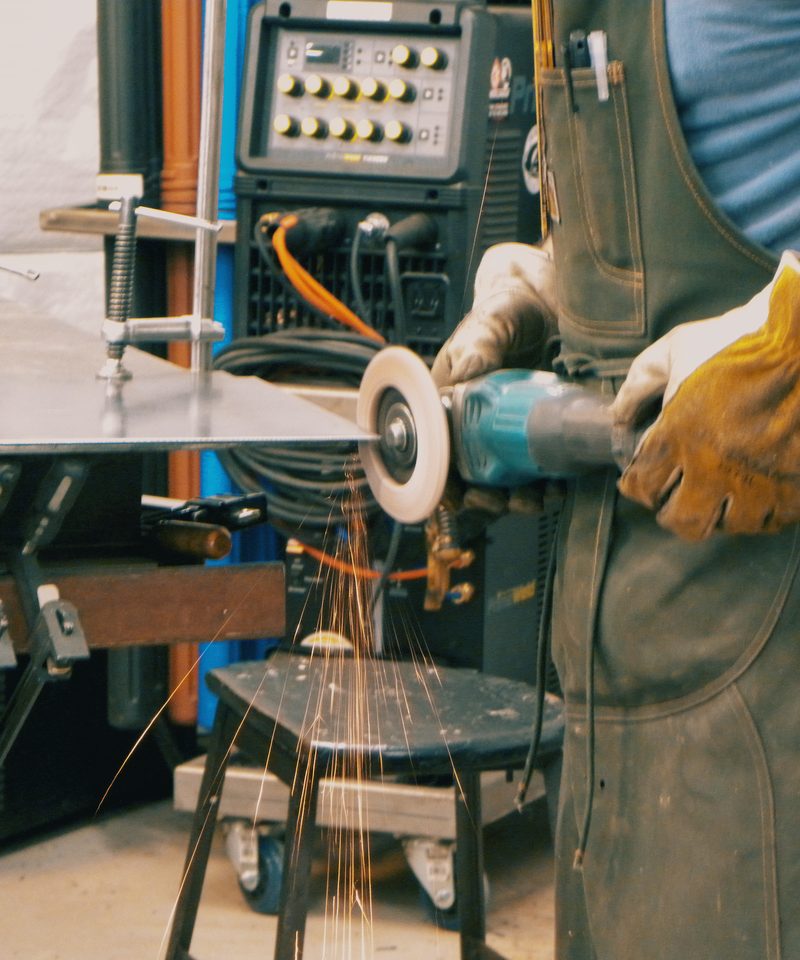 Cutting steel plate with an angle grinder, sparks streaming from the cut